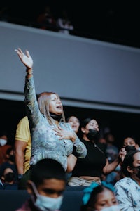 a woman with her hands raised in the air in an auditorium